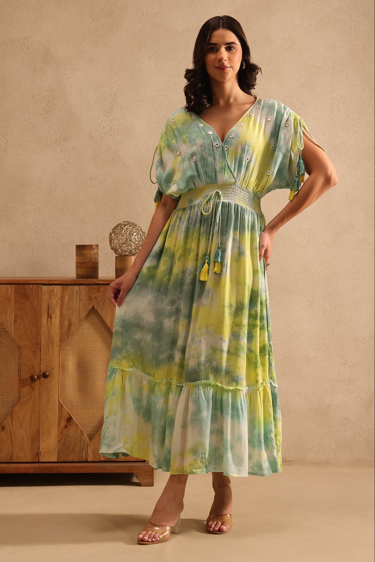 Woman wearing a tie-dye dress from Desi Tassels in a warm-toned room.