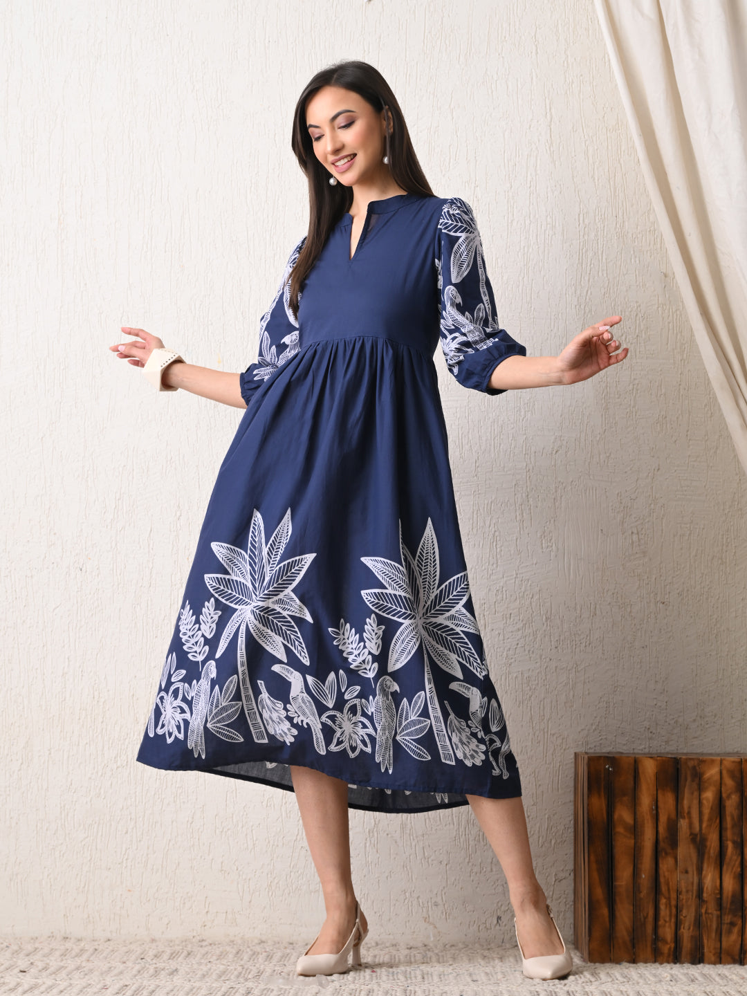 Woman wearing a navy dress with white floral patterns from Desi Tassels against a plain background