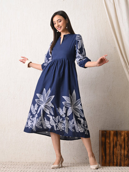 Woman wearing a navy dress with white floral patterns from Desi Tassels against a plain background