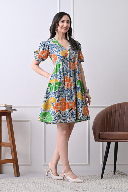 Woman wearing a colorful floral dress from Desi Tassels, standing in a room with a wooden chair and stool.